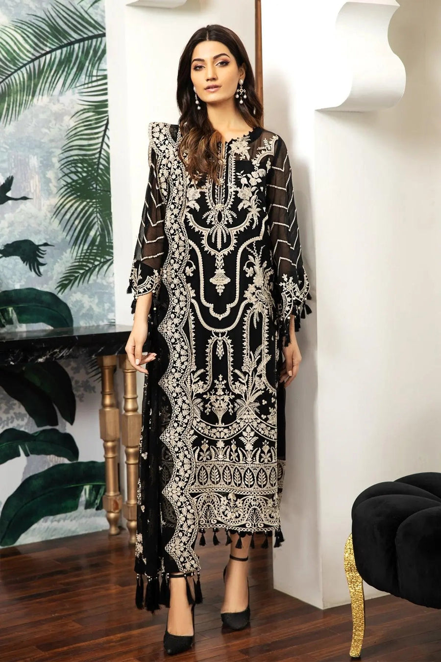 Front view of woman wearing black chiffon suit with ivory embroidery and tassel details