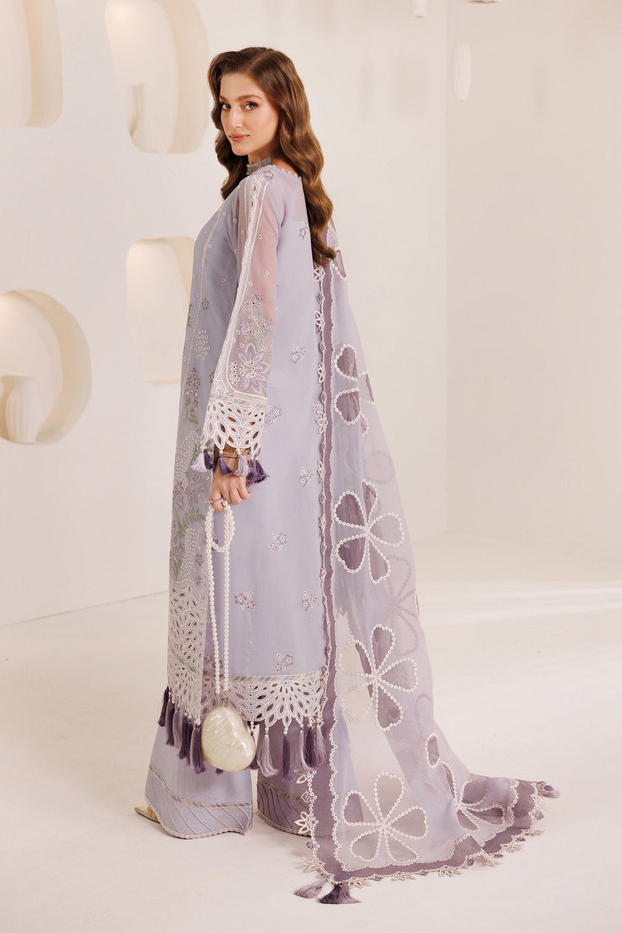 Side view of a woman in light purple embroidered chiffon suit with detailed floral embroidery and tassel sleeves