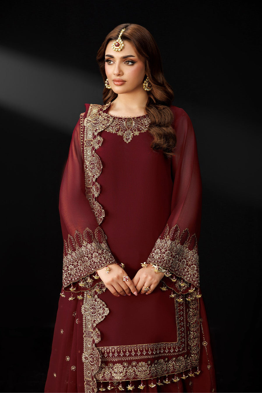 Close-up side profile of woman in maroon embroidered suit with embellished dupatta draped