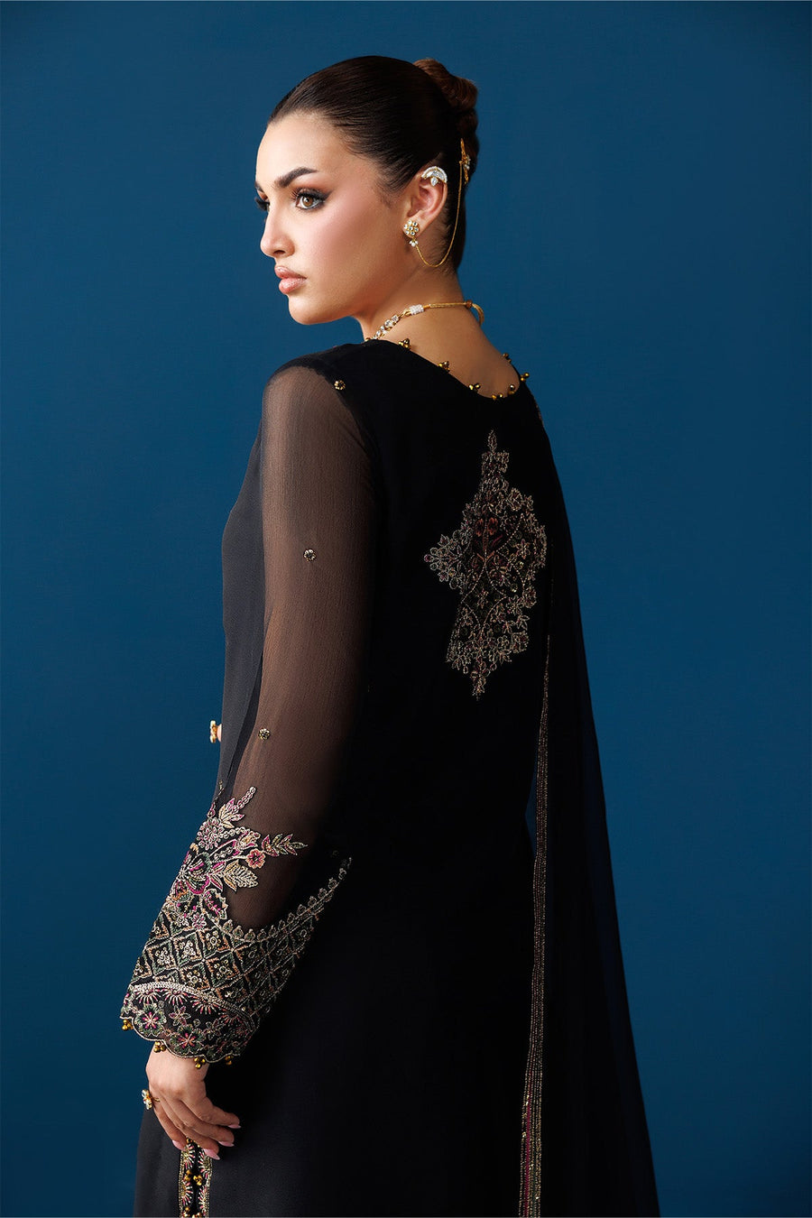 Model posing with embroidered black chiffon dupatta spread out to show border detail