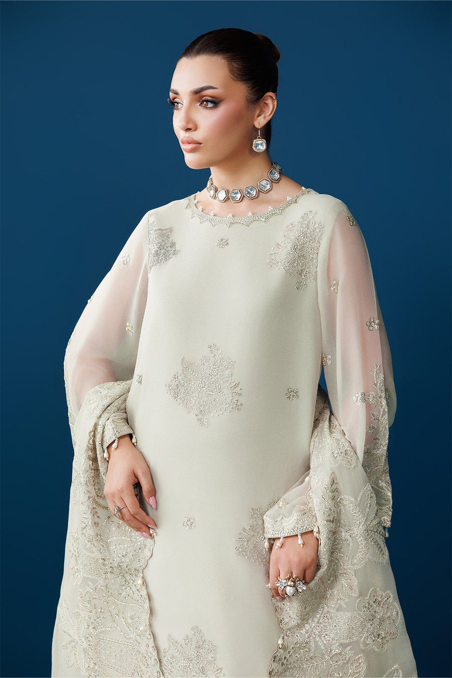 Close-up of embroidered details on front bodice and sheer sleeves with bead tassels