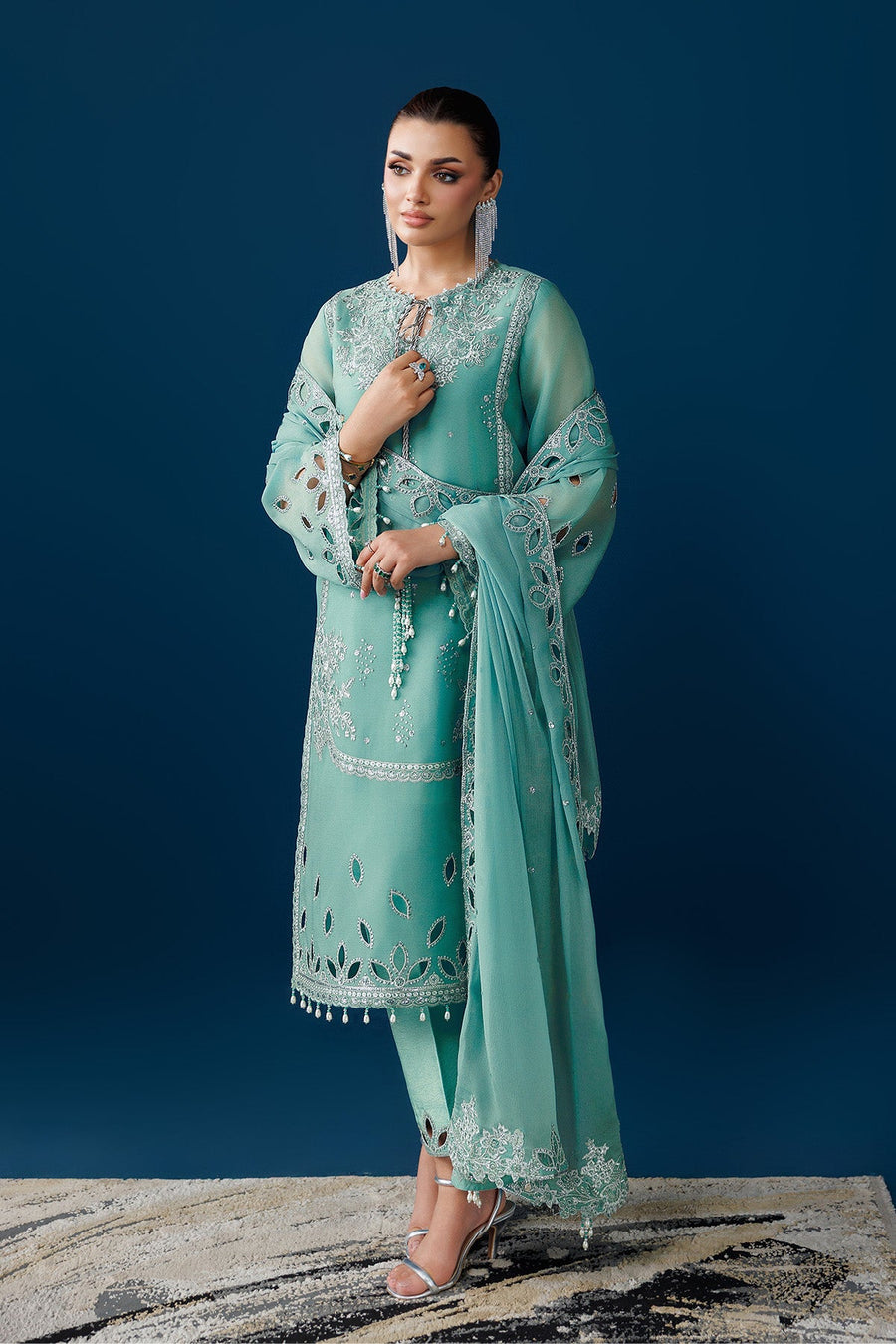 Model holding embroidered dupatta draped over arm showing floral embroidery and mirror cutouts