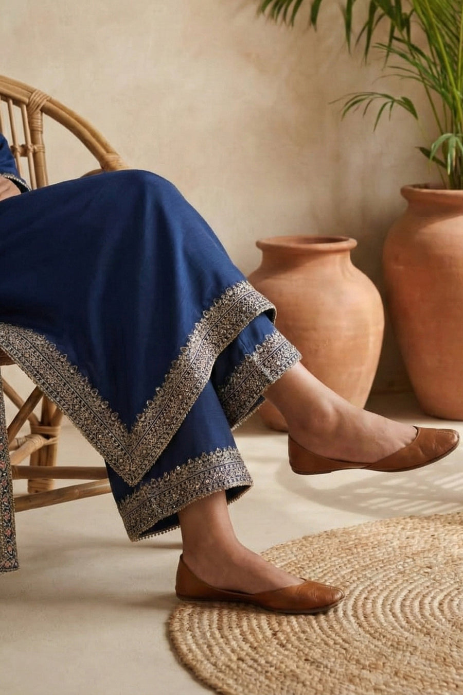 Seated woman showing embroidery on blue kameez and pants with sheer dupatta