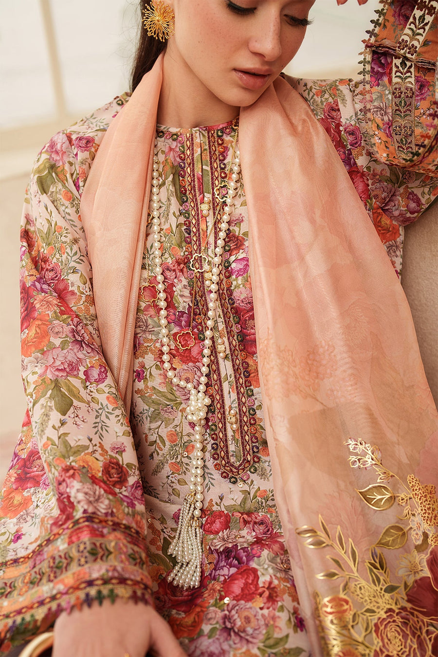 Close-up of neckline embroidery and peach dupatta with delicate floral embroidery and pearl necklace