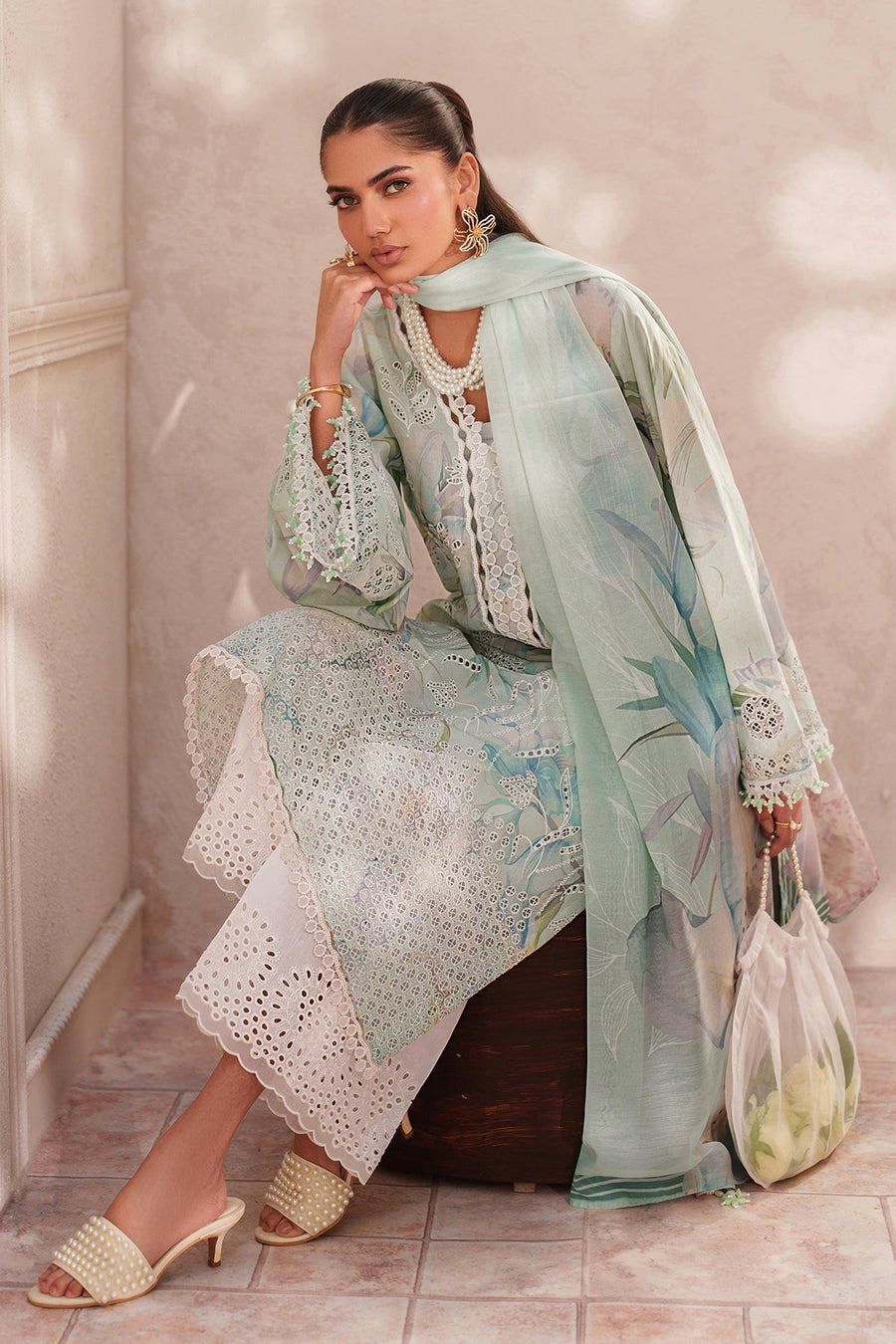 Woman holding delicate sheer white handbag filled with white roses showing fine fabric details and embroidery on sleeves