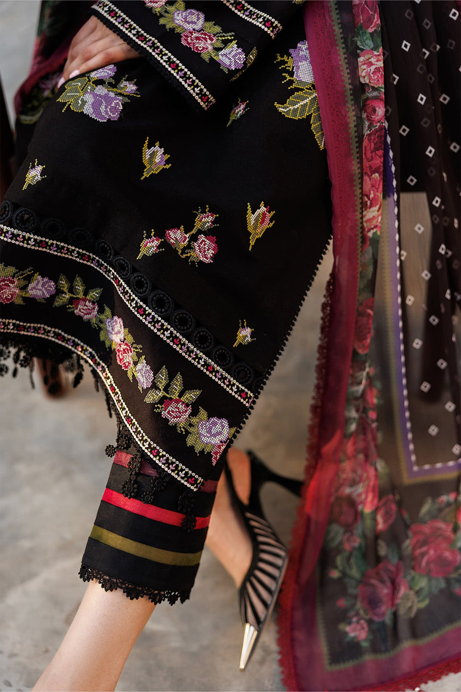Close-up of the embroidered floral sleeve border and lace hem on the striped cotton trousers
