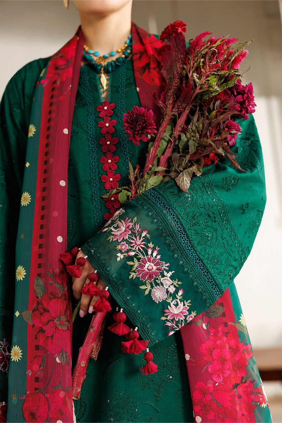 Front full-length view of embroidered three-piece suit with matching green trousers and red floral dupatta