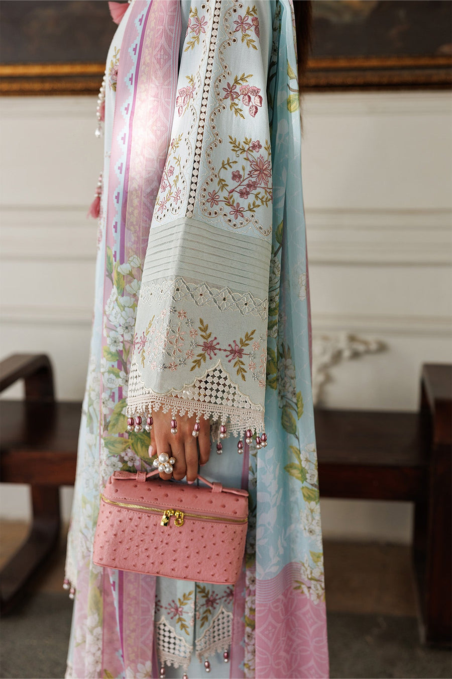 Close-up of sleeve embroidery and lace with beaded tassels on light blue fabric