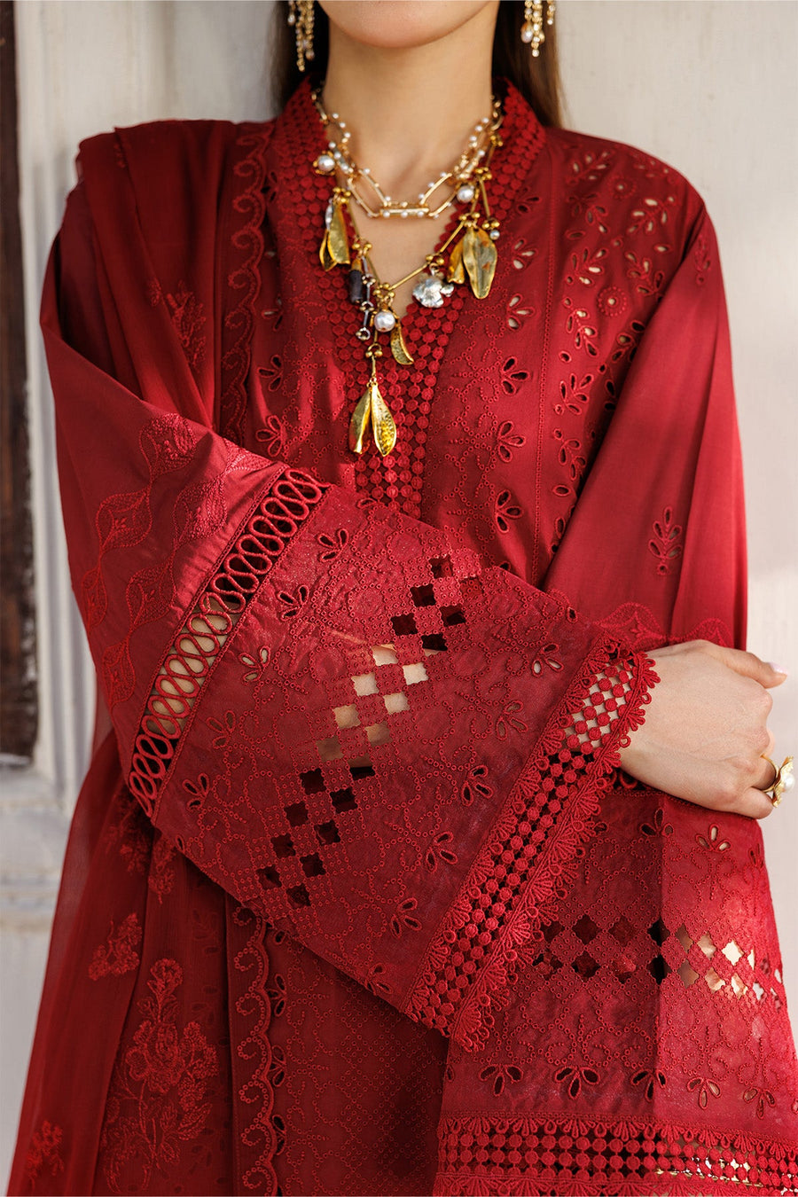Woman draping sheer red chiffon embroidered dupatta over her head in traditional style