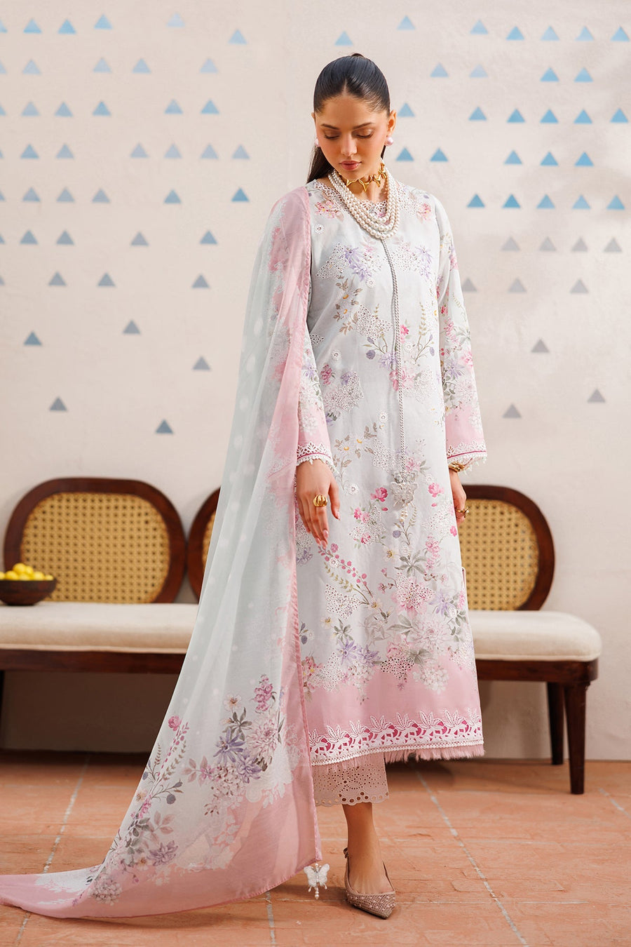 Three-quarter side view of woman wearing pastel floral embroidered lawn suit with soft flowing dupatta draped gracefully