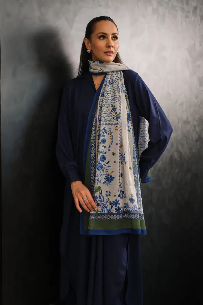 Woman wearing a navy blue outfit with a light-colored embroidered printed scarf featuring blue floral and Urdu calligraphy designs