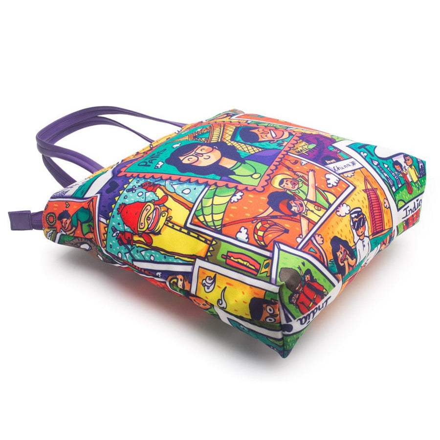 Bottom view of the tote bag displaying the colorful travel collage print and purple handles resting flat