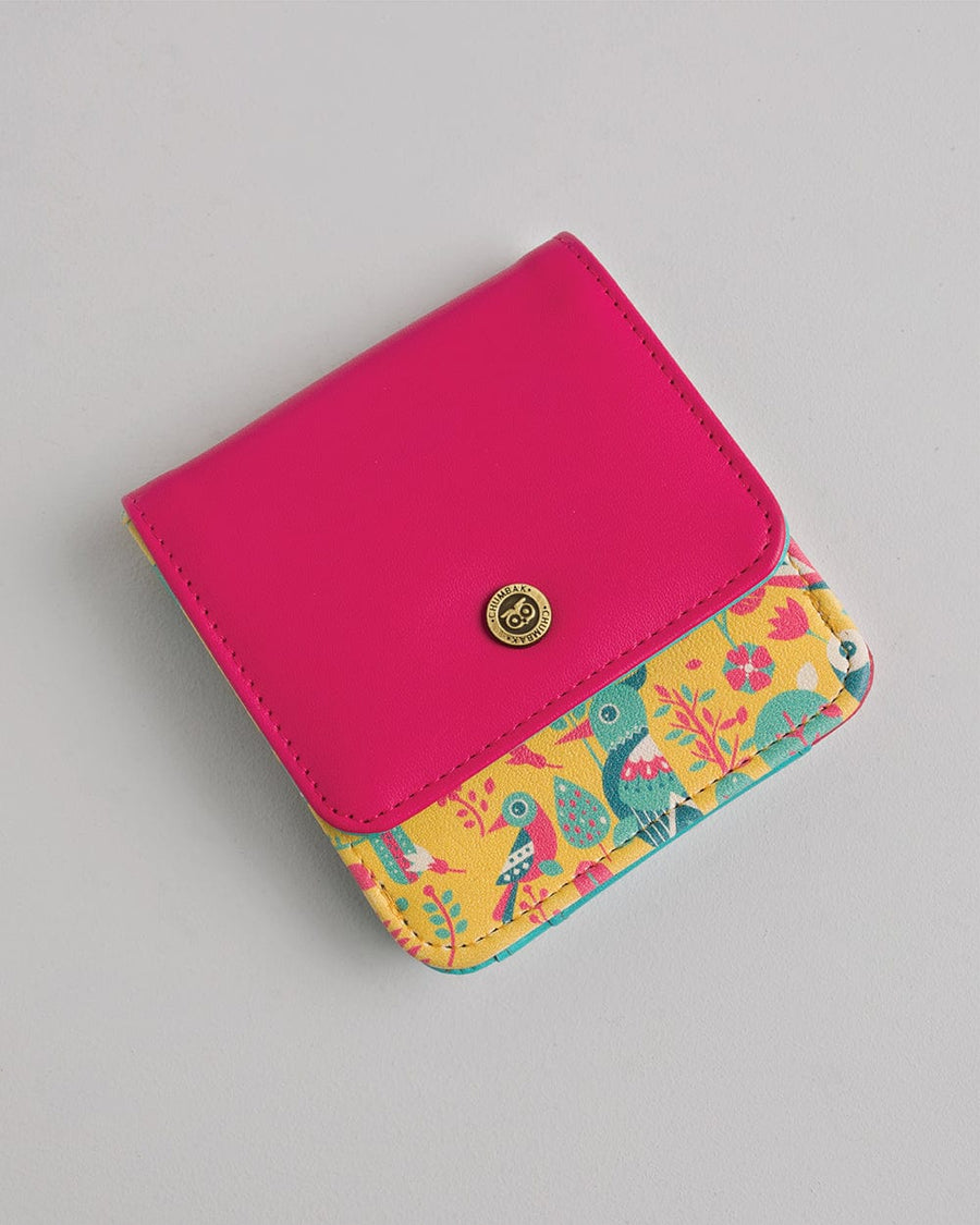 Compact women's bifold wallet with bright pink synthetic leather flap and vibrant yellow bird print base, secured with a gold-tone button