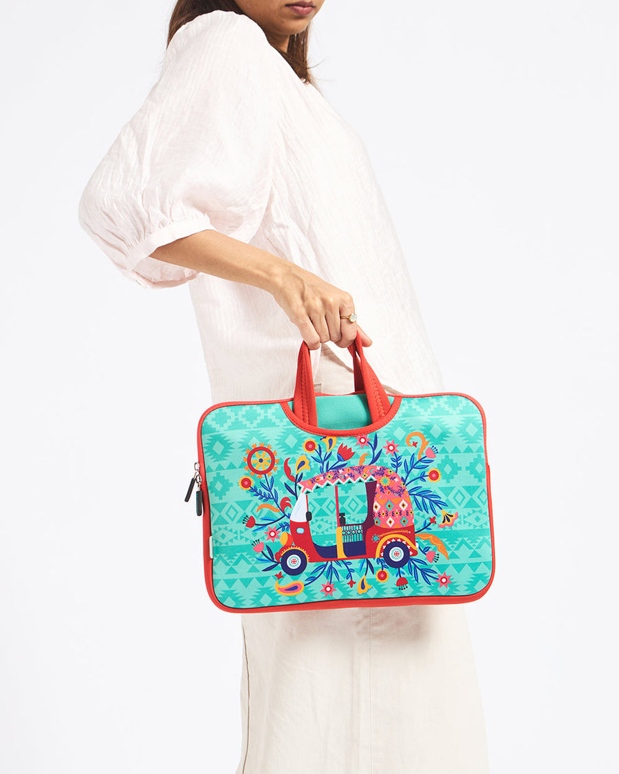 Woman holding a colorful turquoise laptop sleeve with a bohemian auto rickshaw design and orange handles