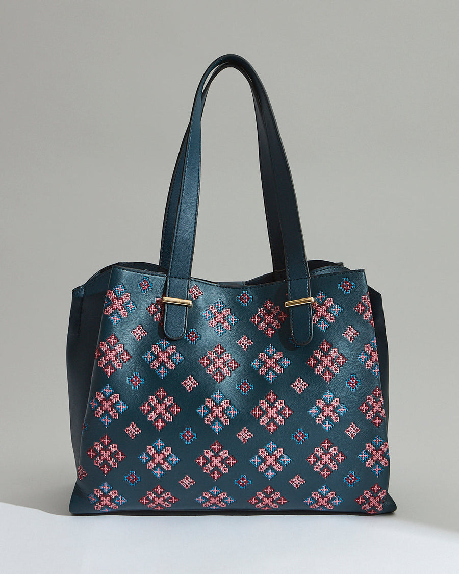 Front view of the deep teal vegan leather tote bag with pink and blue embroidered geometric patterns