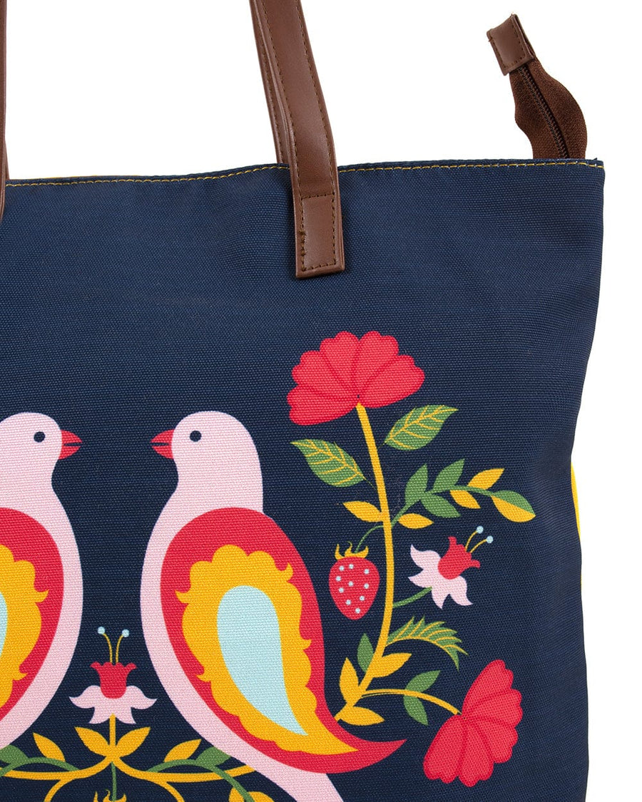 Close-up of the navy blue tote bag showing detailed colorful bird and flower print with brown leather-like strap attachment