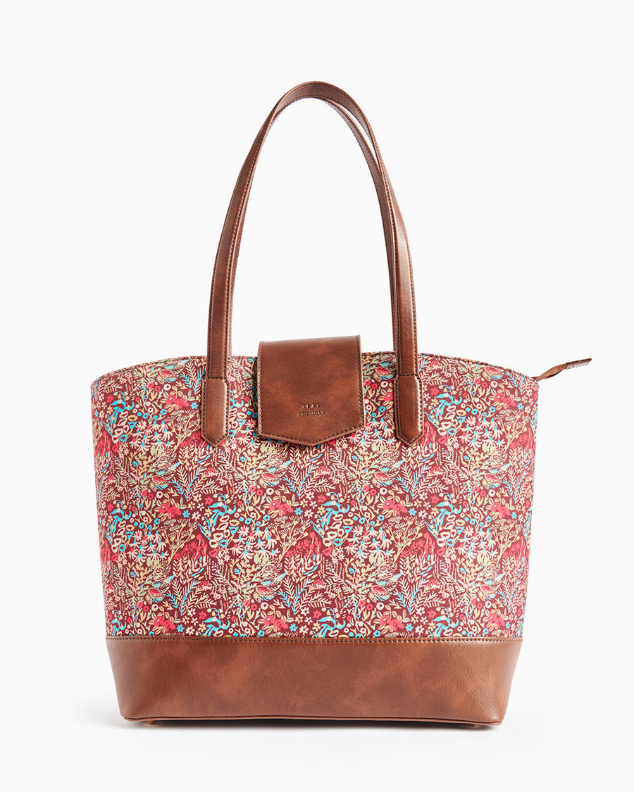 Front view of a floral print tote bag with brown leather base and straps on a white background