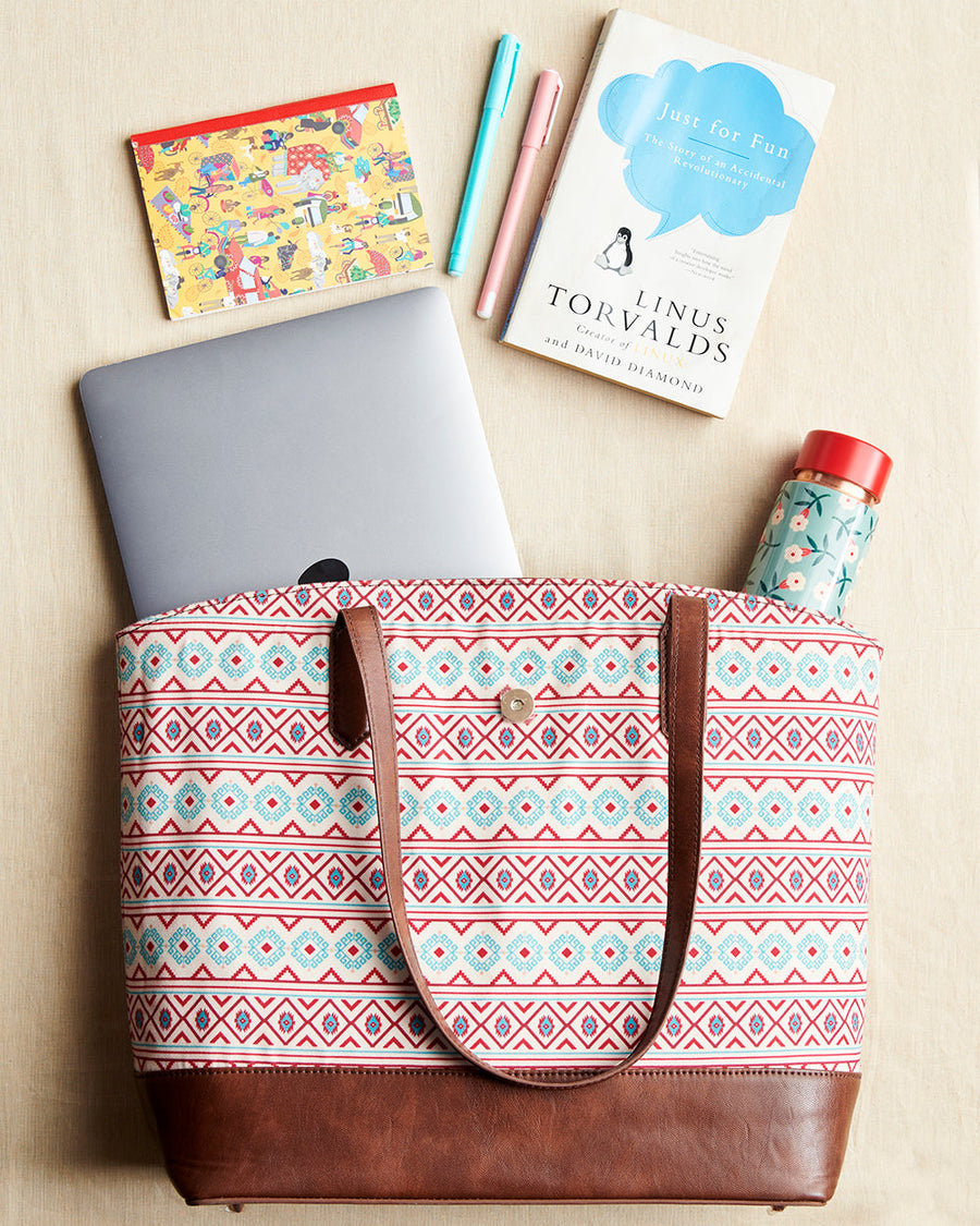 Aztec patterned tote bag open on table with laptop, pen, book, and water bottle nearby