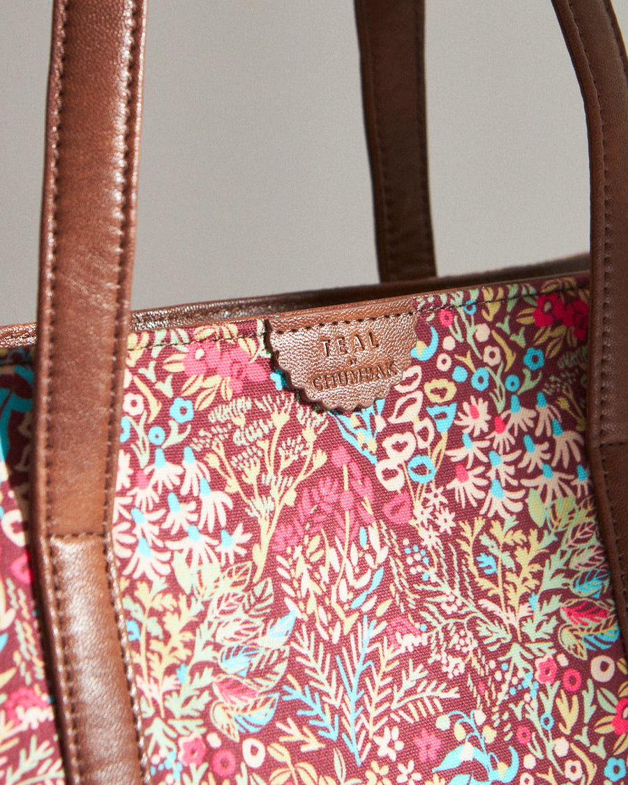 Front view of floral canvas tote bag with annotations highlighting features like vegan leather, magnetic closure, 2 outer pockets, and dimensions