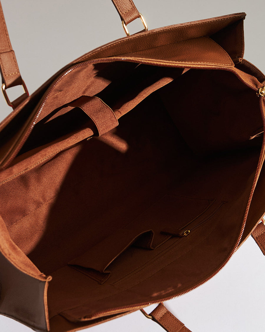 Front view of red floral tote bag with brown vegan leather straps and gold hardware on plain background