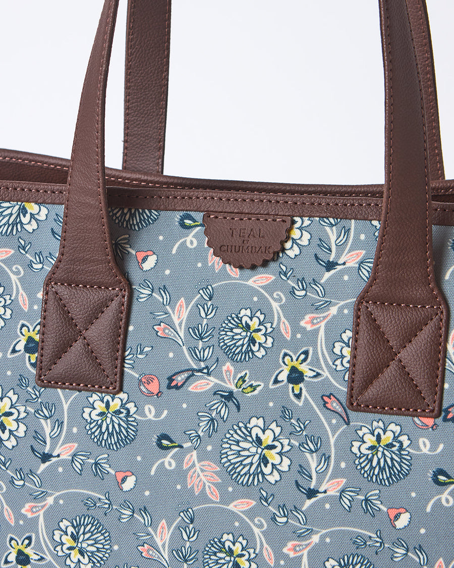 Overhead view of open tote bag showing laptop, notebook, and charger inside organized pockets