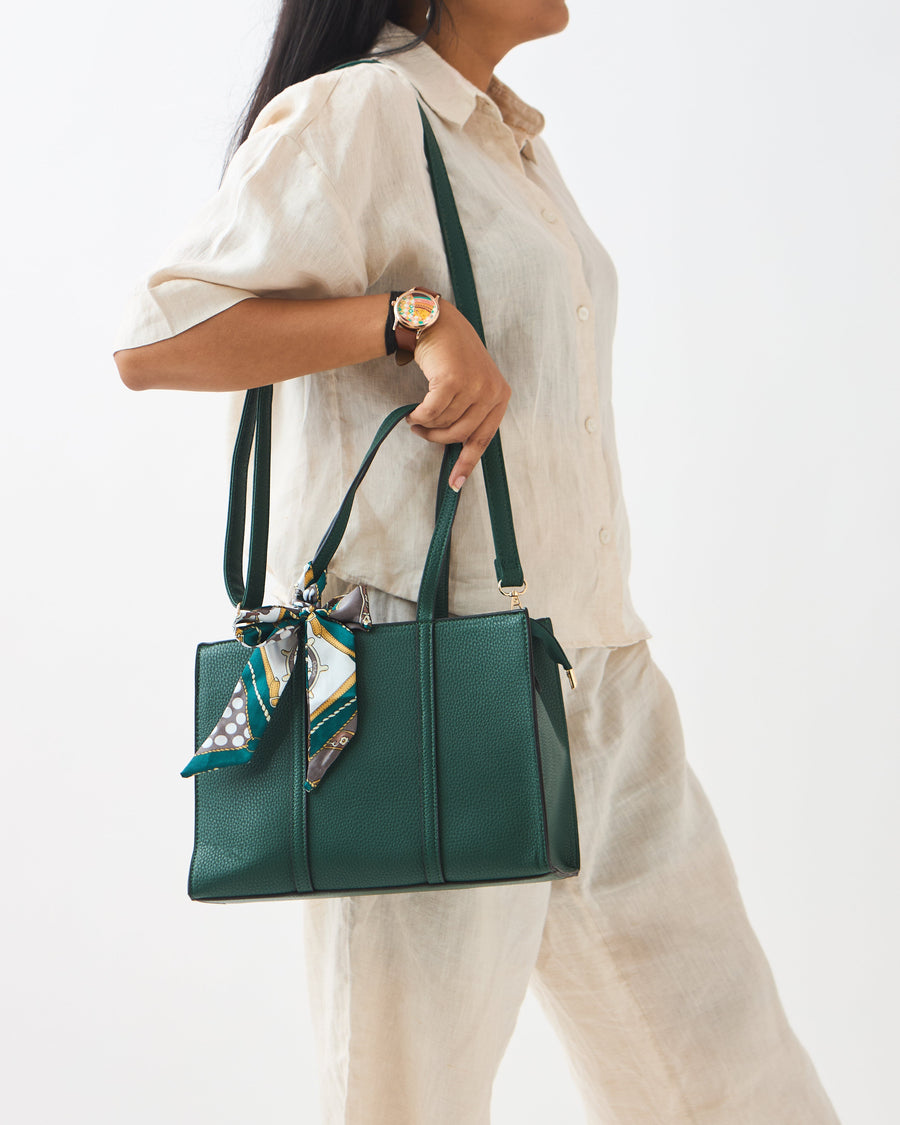 Close-up side view of woman carrying green mini tote with long shoulder strap and printed scarf