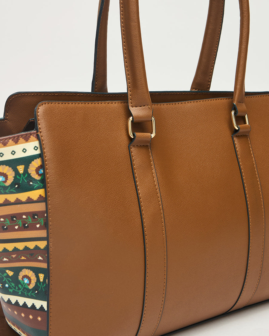 Close-up of Kenya Tote bag front leather surface and handles with gold-tone metal hardware