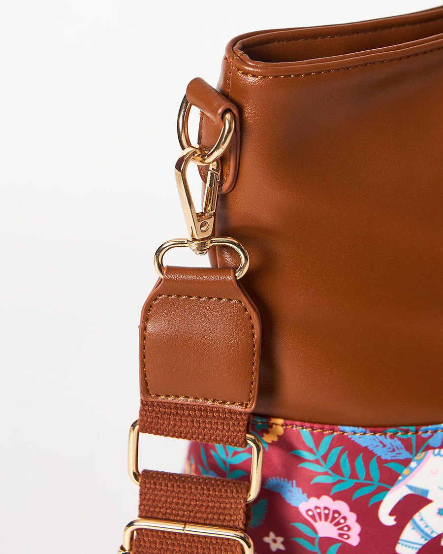 Close-up of gold-toned clasp and adjustable brown strap attaching to the bag