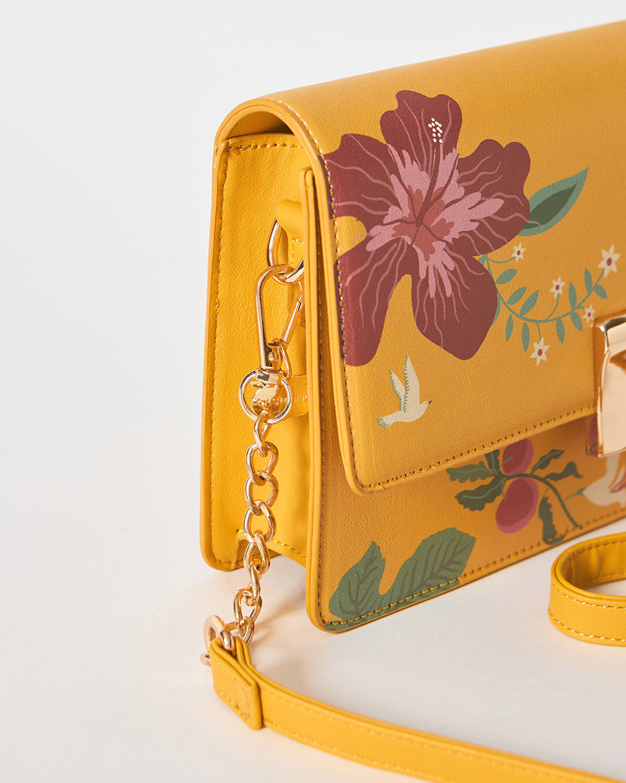 Close-up side view of mustard yellow floral shoulder bag with gold chain strap attachment