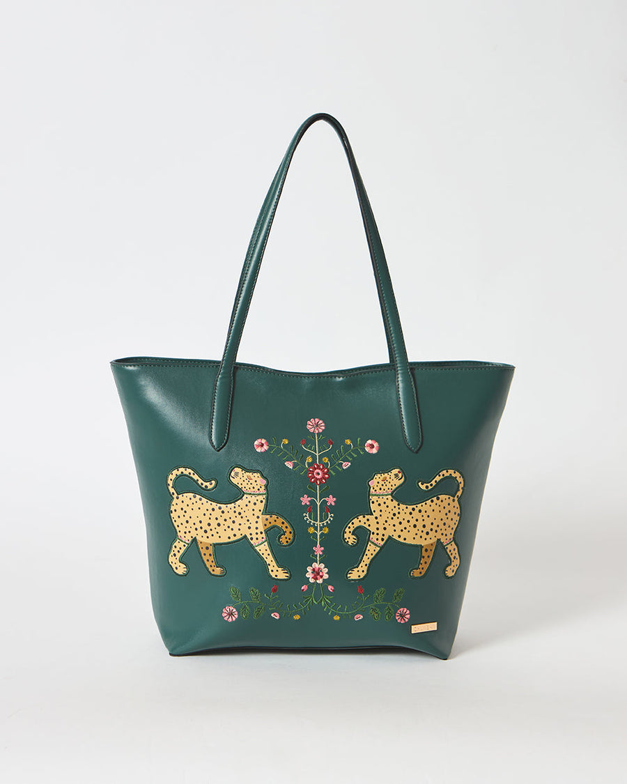 Close-up front view of deep green vegan leather tote bag featuring embroidered yellow leopards and floral designs on plain white background