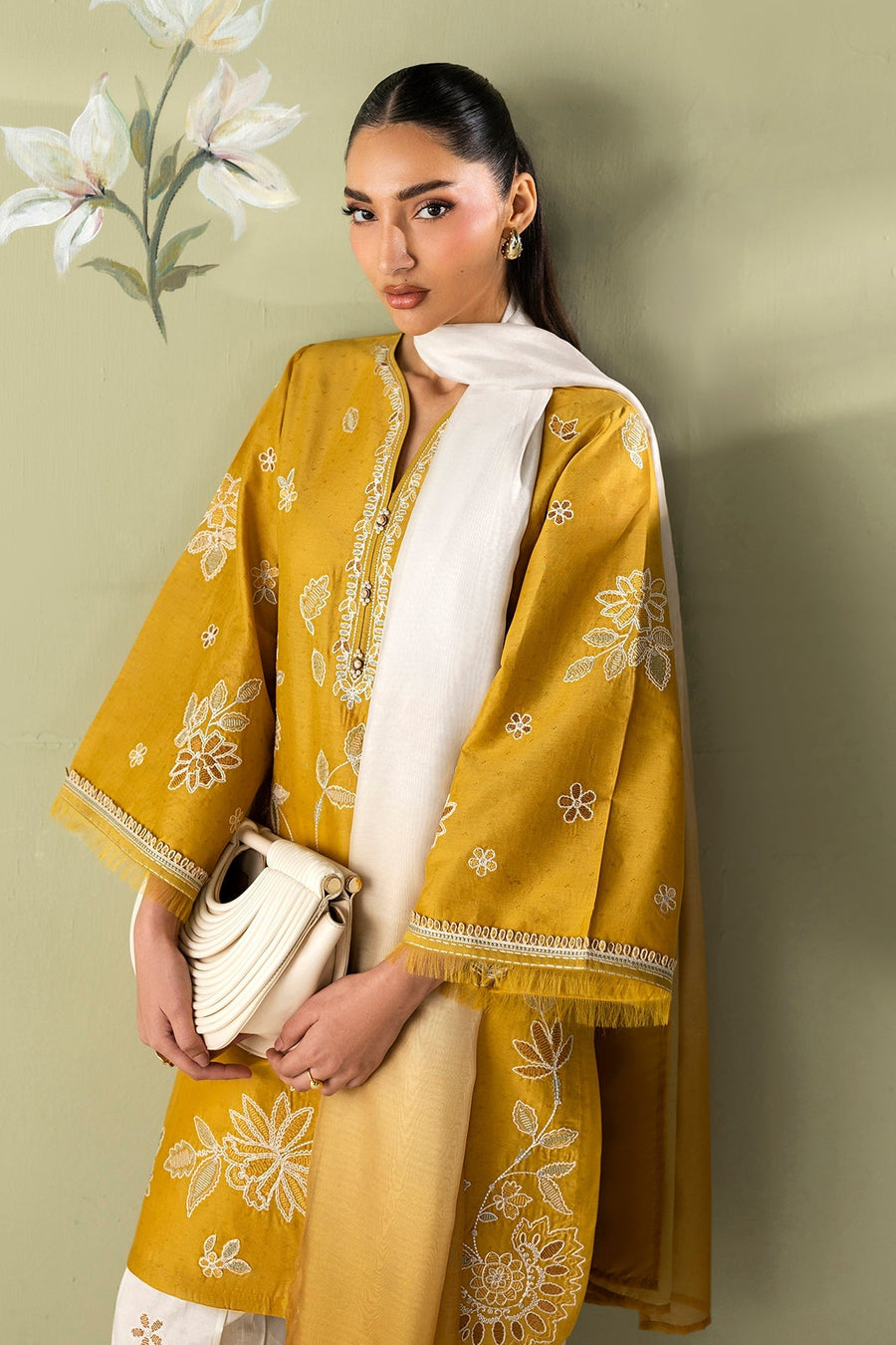 Close-up side view of model holding off-white handbag with embroidered mustard yellow shirt and ombré dupatta