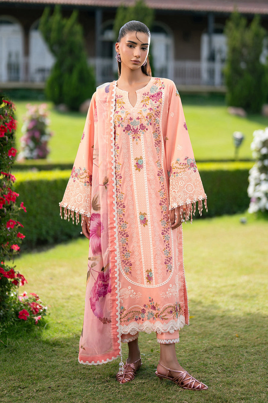Woman wearing peach embroidered lawn suit with floral design and chiffon dupatta outdoors