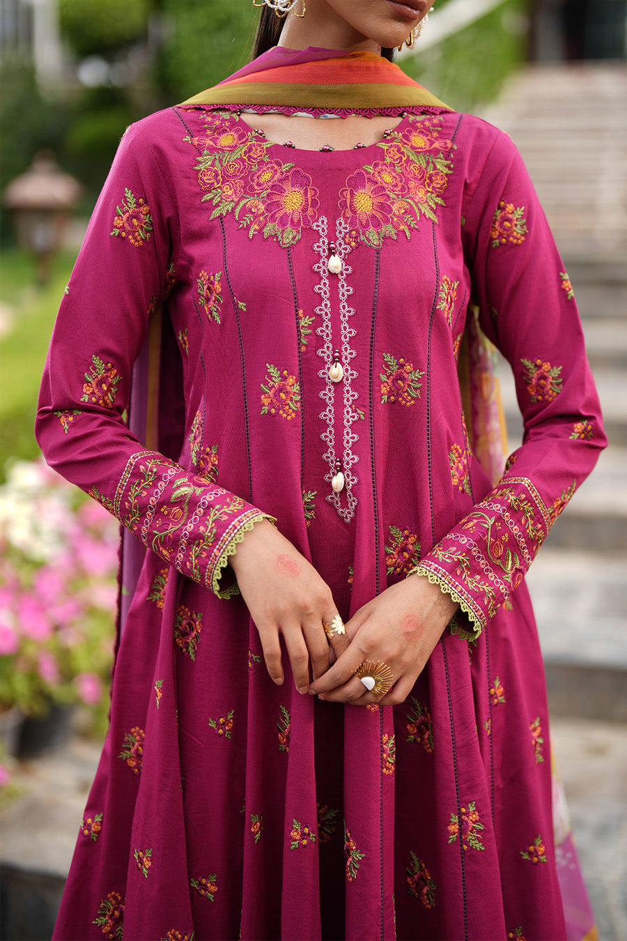 Woman holding basket of flowers wearing magenta floral maxi dress with embroidered sleeves