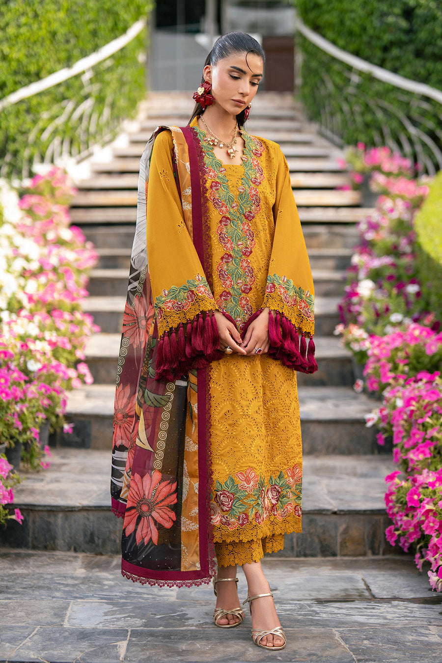 Side view of woman wearing embroidered lawn suit in mustard yellow with maroon tasseled sleeves