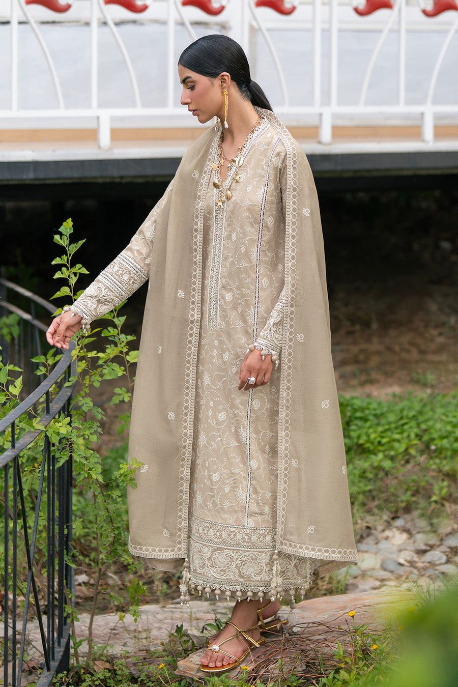 Close-up of model wearing embroidered lawn suit with gold earrings and delicate necklace