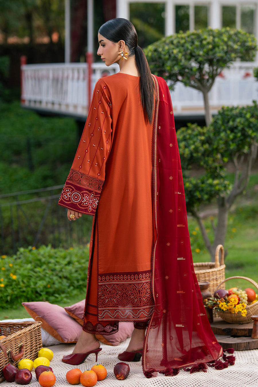Back view of embroidered rust orange lawn suit with maroon dupatta draped over shoulder