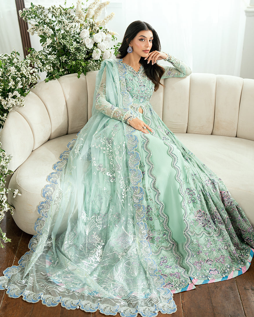 Seated woman in embroidered chiffon dress with coordinating dupatta draped over arm showing ornate border