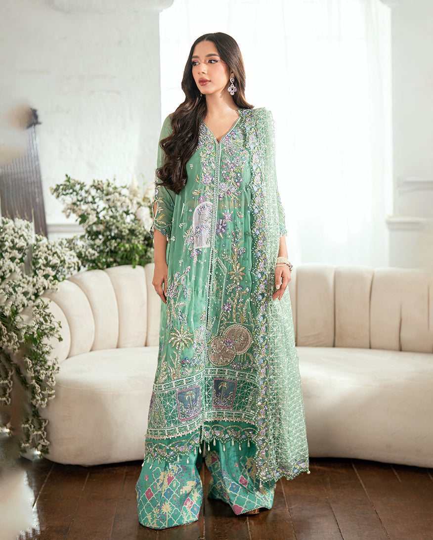 Woman wearing a soft green embroidered chiffon formal suit with detailed floral and geometric patterns standing in a bright room