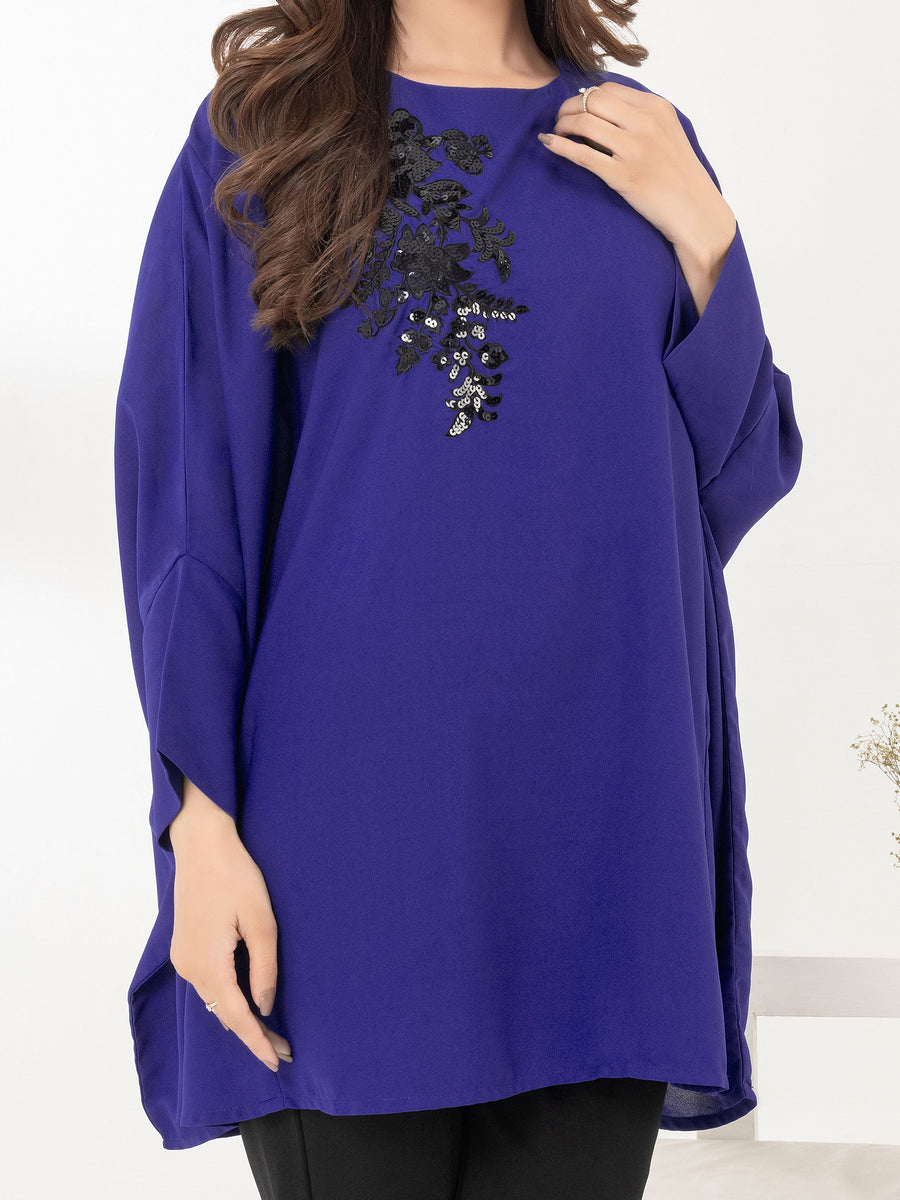 Close-up view of upper front of royal blue loose fit top highlighting black sequin embroidery and fabric texture