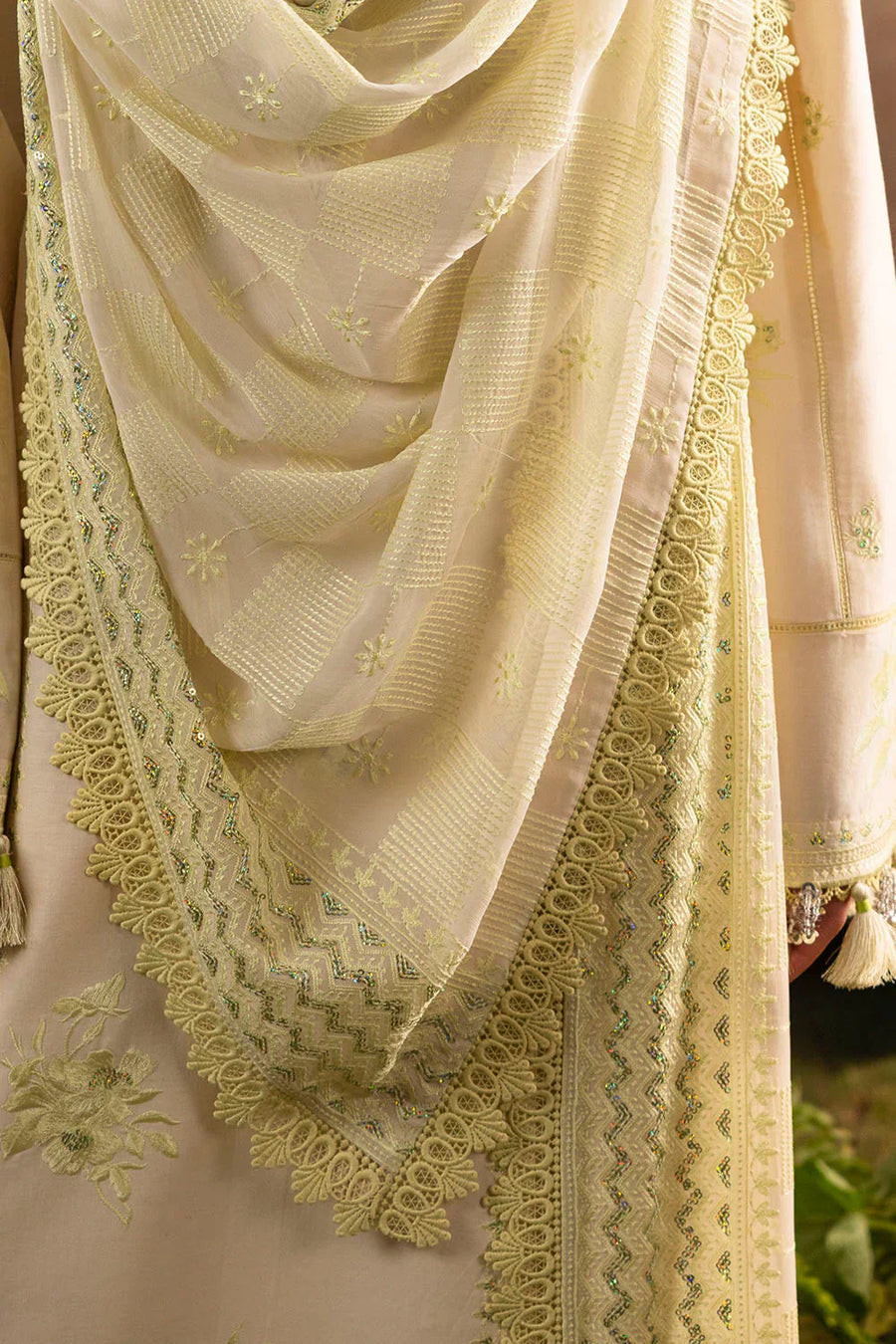 Woman wearing pastel cream embroidered lawn suit styled with detachable chiffon dupatta in soft floral embroidery and tasseled border