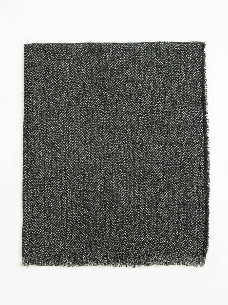 Close-up of charcoal wool shawl folded flat, showing subtle herringbone weave and fringed edge detail