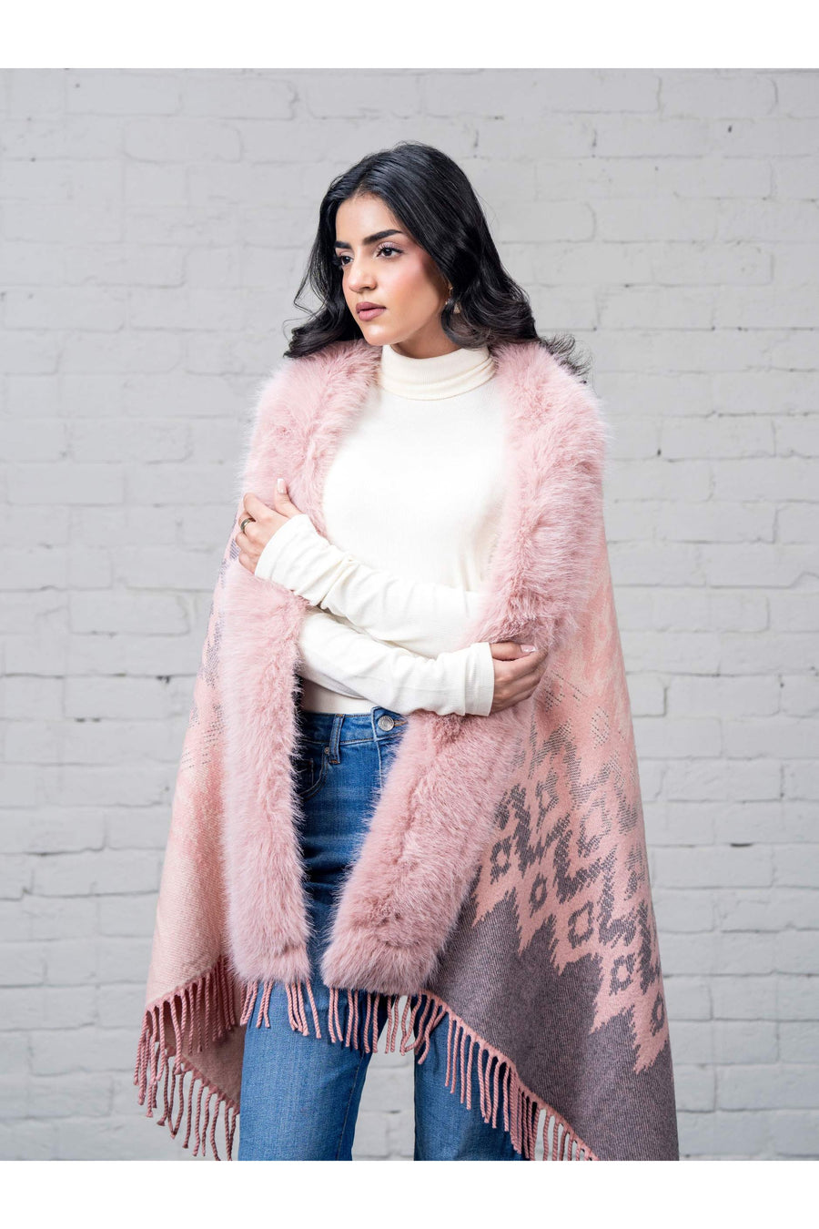 Close-up front angle of woman wrapped in pink faux fur trimmed wool cape with intricate pattern, soft waves hairstyle