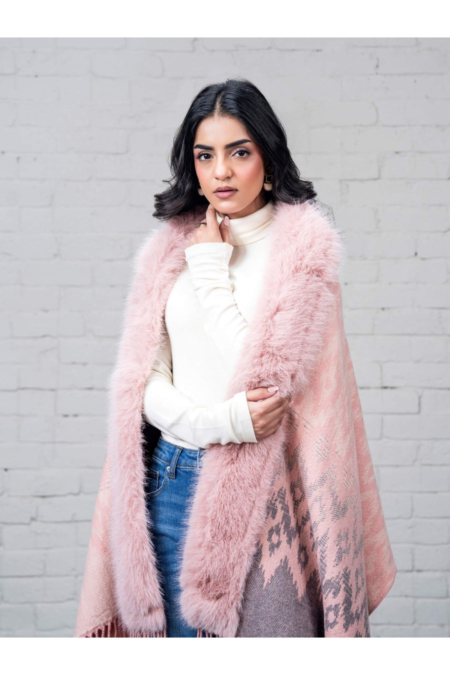 Medium close-up of woman wrapped in pink cape with faux fur collar trim, displaying texture and pattern details
