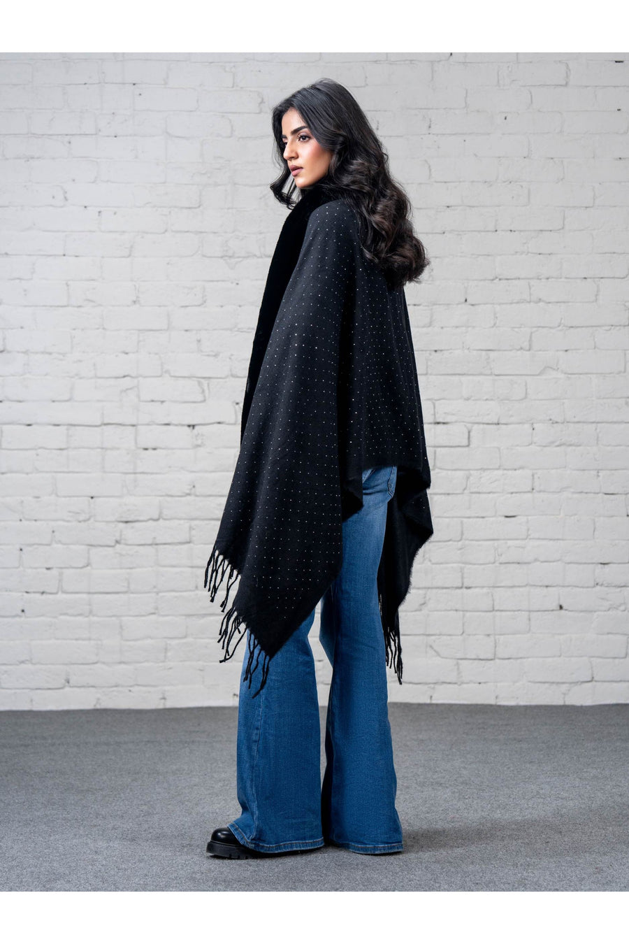 Close-up side shot of woman wearing black wool cape shawl revealing plush faux fur collar and delicate rhinestone embellishments