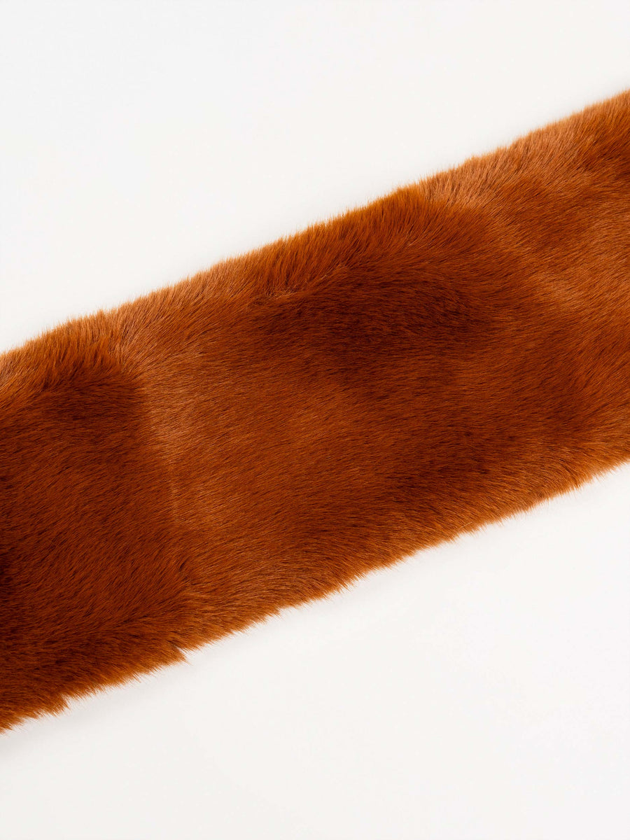 Close-up of the rust brown plush fur muffler's soft fur texture on a white background