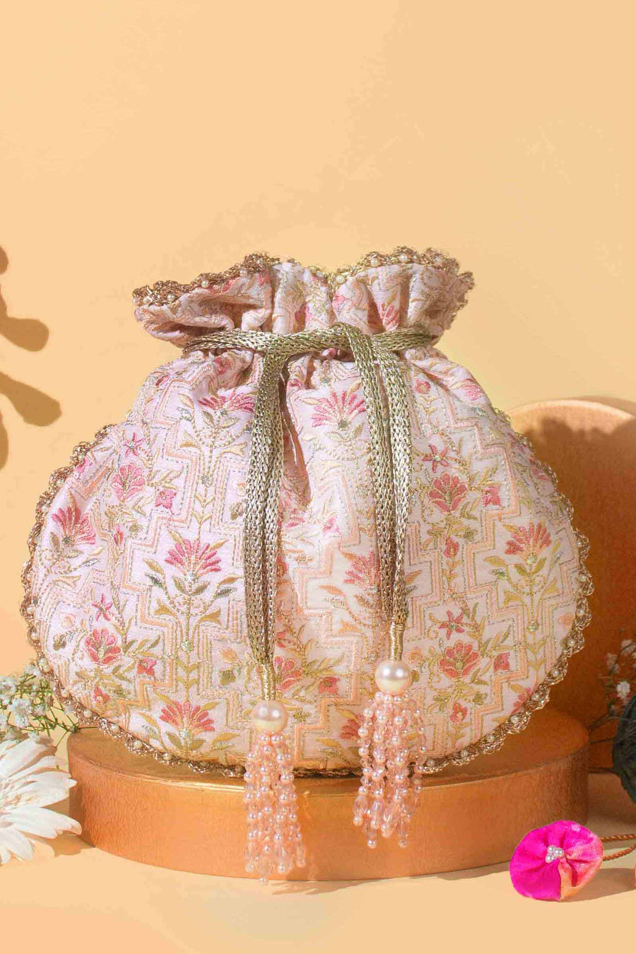Elegant baby pink scallop-edged potli bag with intricate floral embroidery and pearl tassel drawstrings