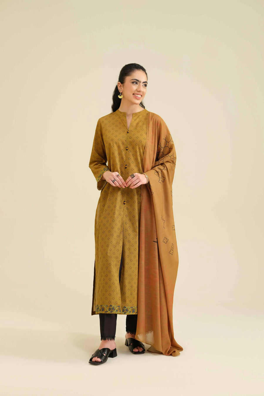 Model smiling while holding dupatta showing black motif designs