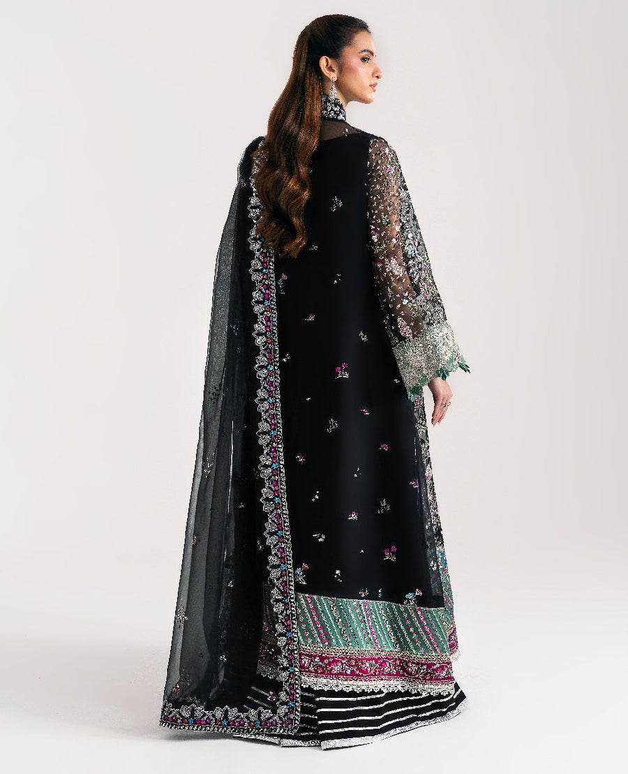 Back view of model displaying embroidered black organza shirt with sheer sleeves and matching dupatta draped over shoulder
