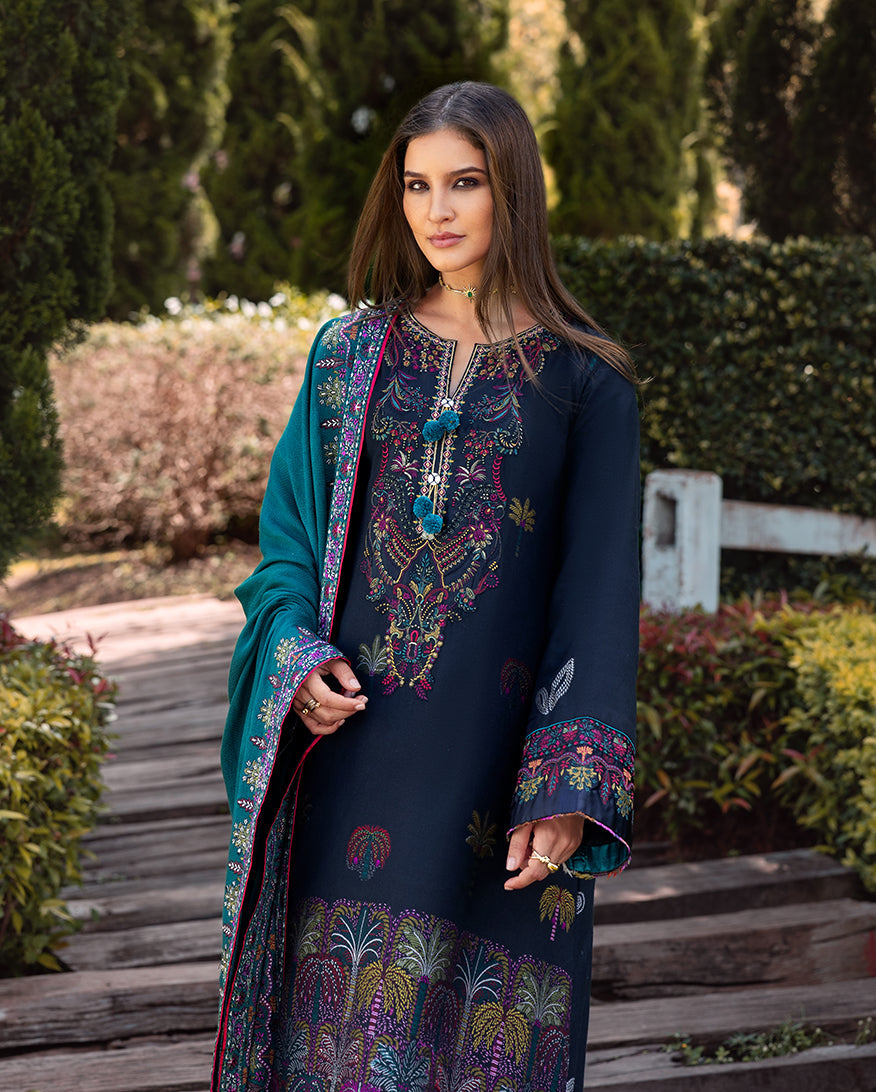 Close-up of woman wearing navy blue embroidered winter suit with tassel detailing on neckline and matching teal shawl