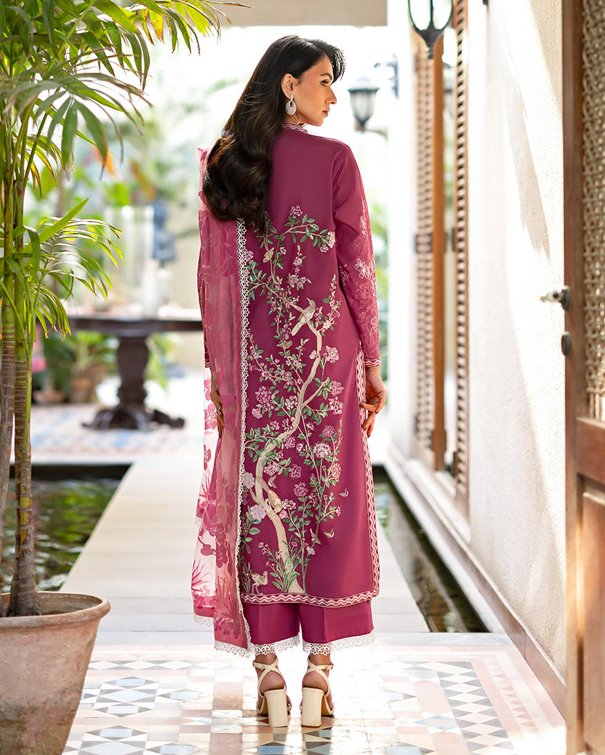Back view of woman in magenta lawn suit displaying intricate floral embroidery along the back and sheer floral dupatta